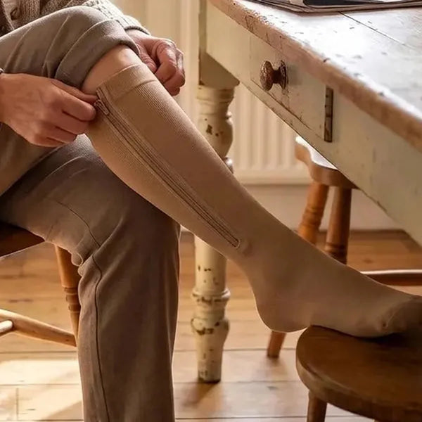 Chaussette de compression beige portée sous un pantalon, fermeture éclair invisible de l'extérieur