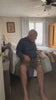Homme senior qui enfile seul sa chaussette de compression zippée, assis au bord du lit